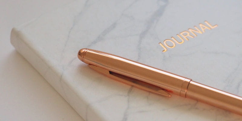 caneta dourada e caderno branco