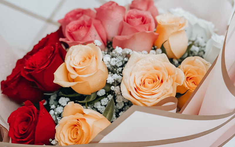 Vista de cima de buquê de flores com rosas vermelhas, rosas e amarelas.