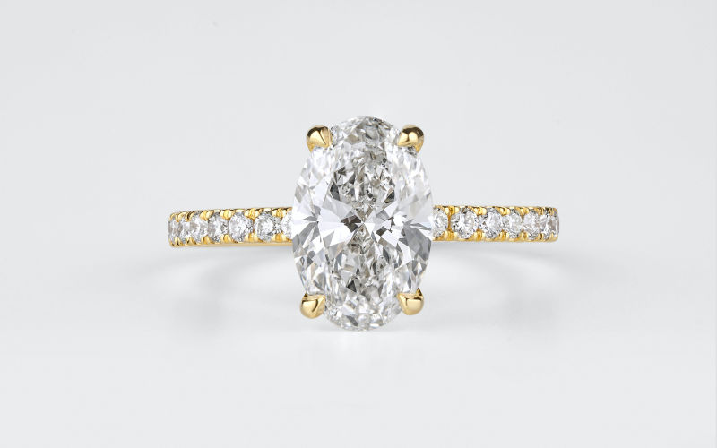 Vista de frente de um anel dourado com pedras cristalinas em um fundo branco